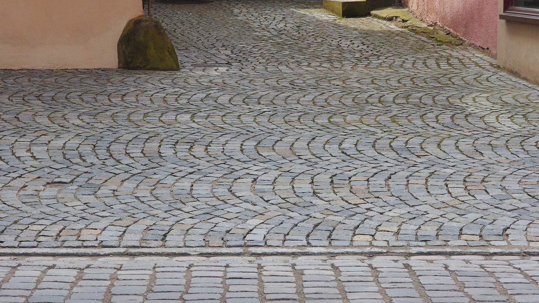 Gehweg und Straße mit unterschiedlicher Pflasterung.