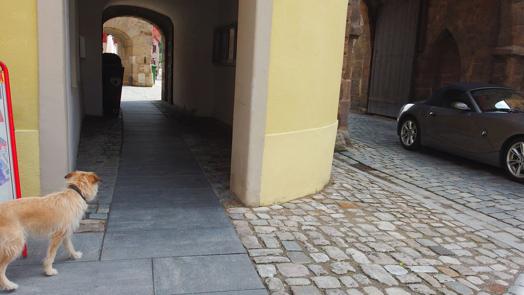Blick auf Stadttor mit Gehweg und Fahrbahn; der Gehweg ist durch ein Laufband barrierefrei erschlossen.