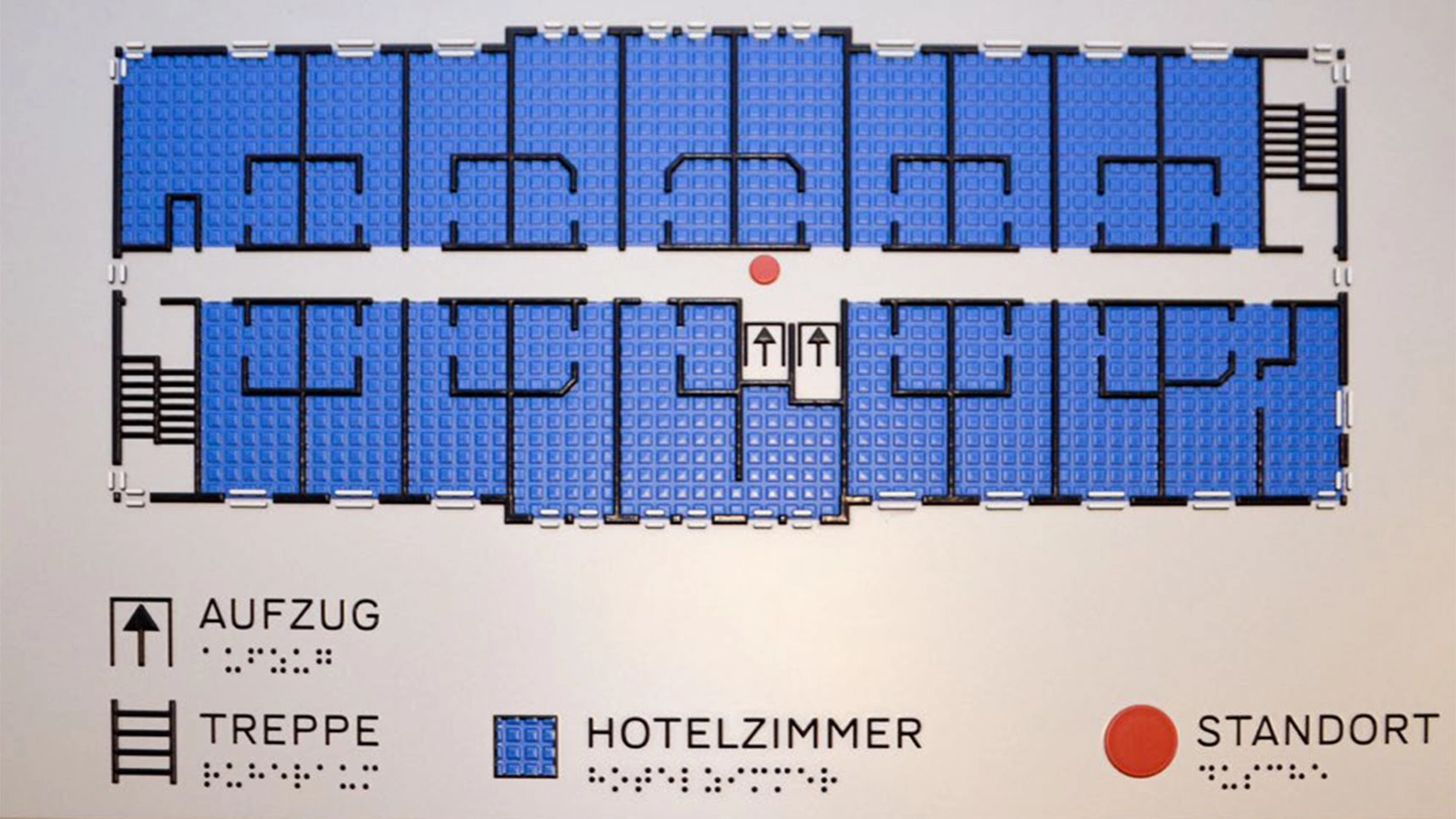 Nahaufnahme einer Infotafel mit taktilem Leitsystem einer Gebäudeetage.