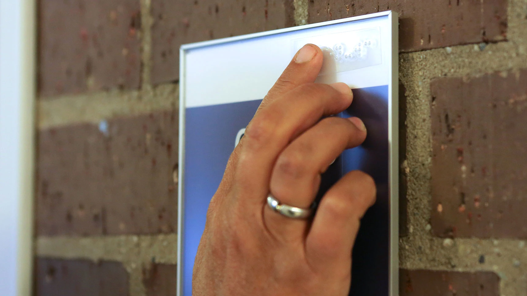 Eine Hand ertastet die Brailleaufschrift auf einem Schild.