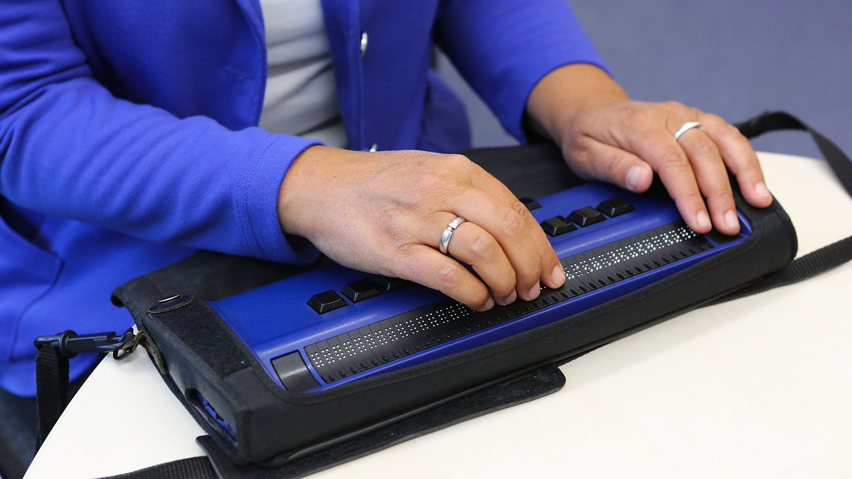 Nahaufnahme: Hände auf einer Braillezeile.