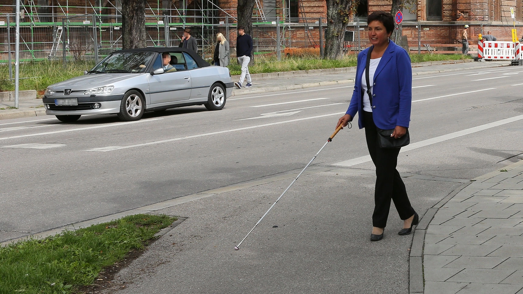 Irmgard Badura tritt vom Gehweg auf eine Fahrradspur. Fuß- und Radweg sind sichtbar, aber nicht taktil erfassbar voneinander abgesetzt.