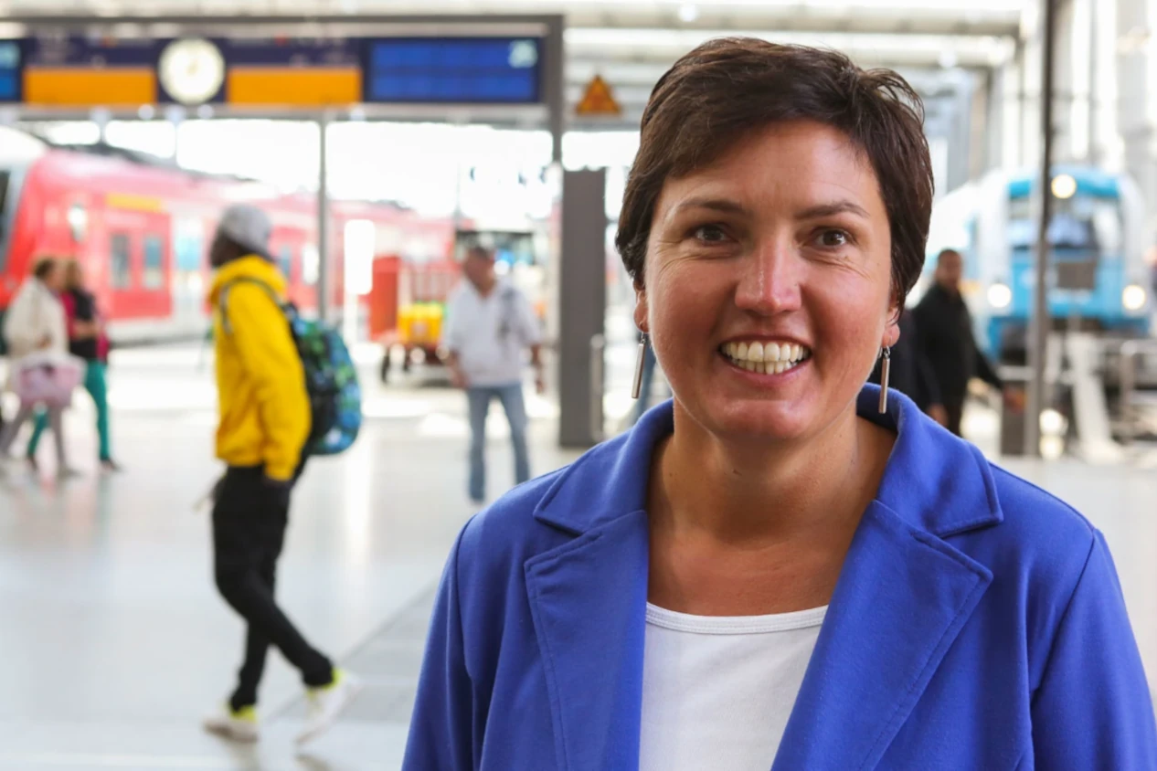 Porträtfoto von Irmgard Badura; im Hintergrund ist die Halle des Münchner Hauptbahnhofs zu sehen.