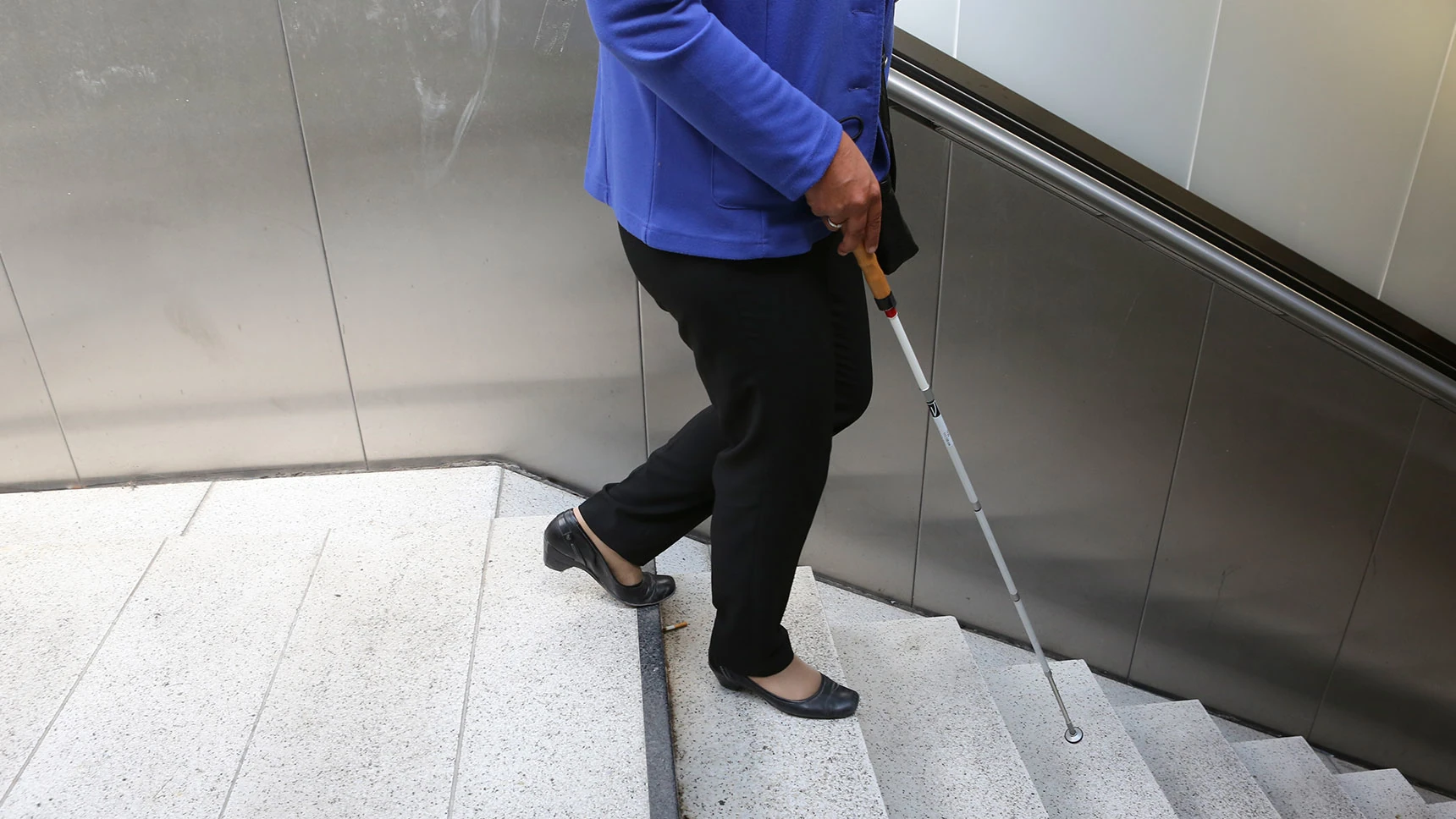 Irmgard Badura auf der ersten Stufe einer Treppe, die ins Bahnhofs-Zwischengeschoss führt.