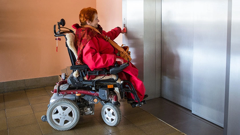 Dinah Radtke mit Rollstuhl vor einem Lift.