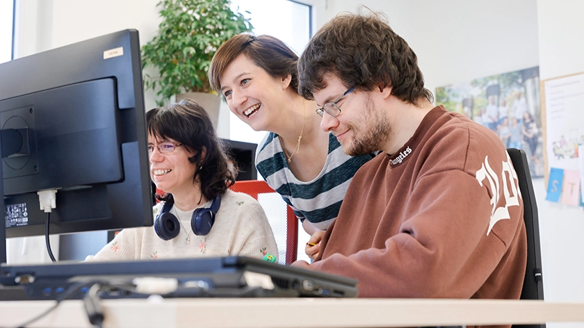 Maria Hütter-Songailo, Carola Nagel und Denis Schreiber bei der Zusammenarbeit an einem Schreibtisch.