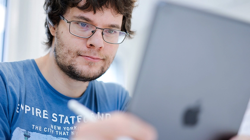 Denis Schreiber schaut konzentriert auf ein Tablet.