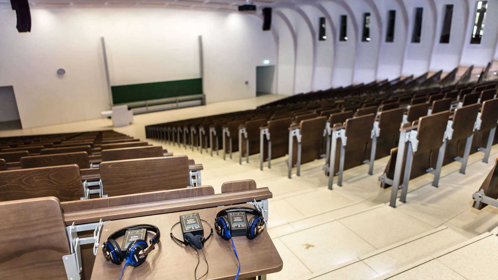 Großer Hörsaal; auf einem Tisch liegen Kopfhörer.