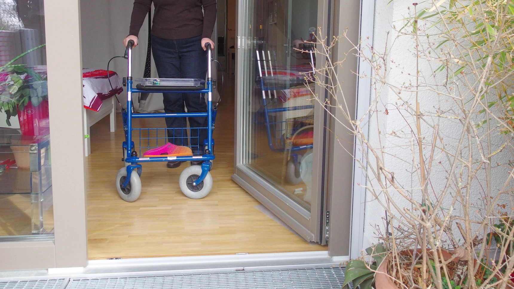 Karin K. steuert mit dem Rollator aus der Wohnung auf den Balkon zu.